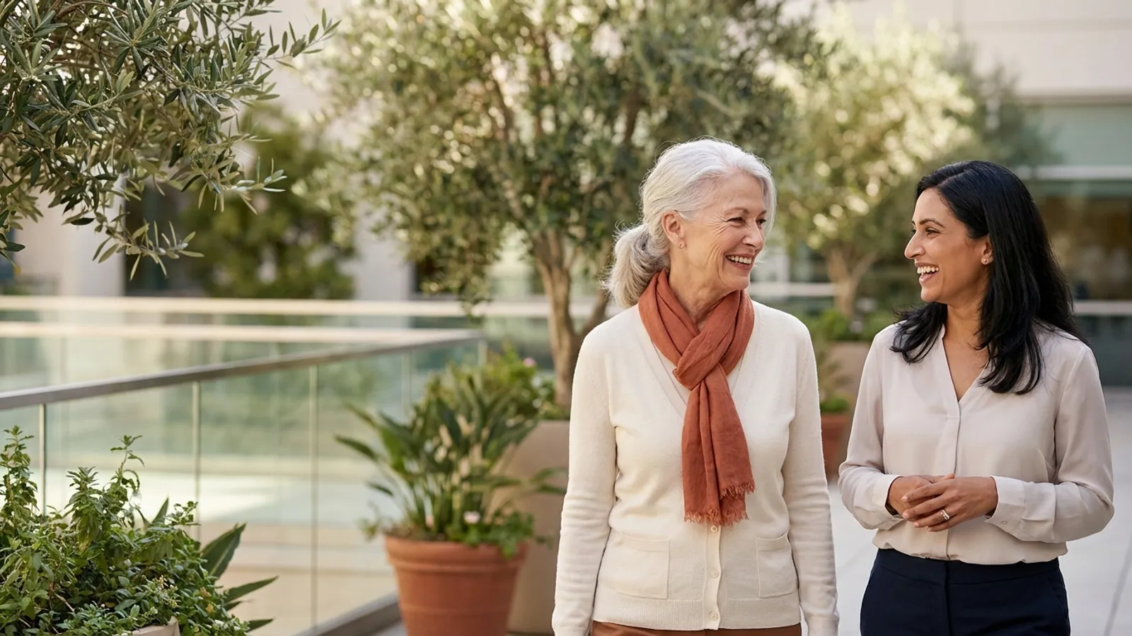 An energetic senior woman smiling and conversing with her cardiologist on a sunlit hospital garden terrace after a heart valve consultation.